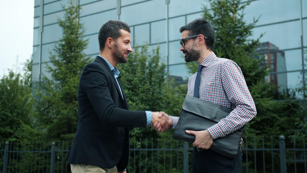 Two professionals shaking hands outside a modern office building